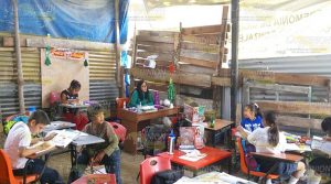 Estudian en aula de madera y palos