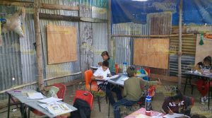 Estudian en aula de madera y palos