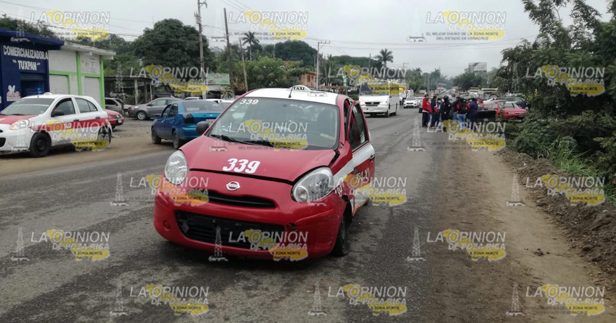 Intenta rebasar y choca con un taxi