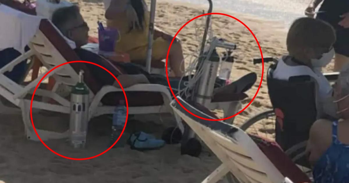 Hombre toma el sol en la playa con todo y tanques de oxígeno